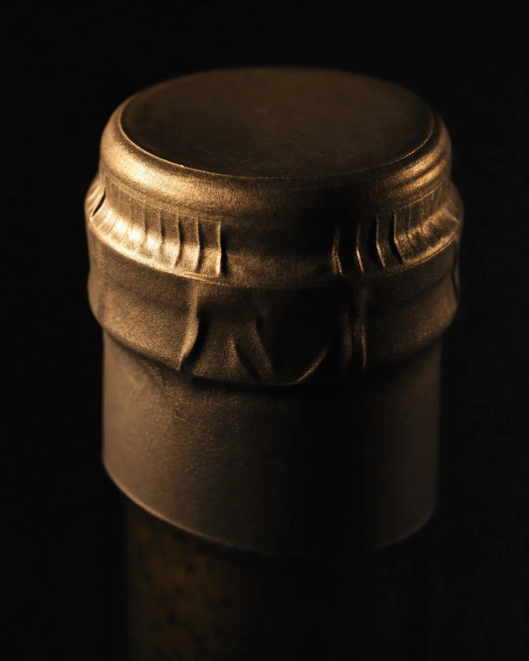 Macro of a plain tin capsule crimped over a cork.