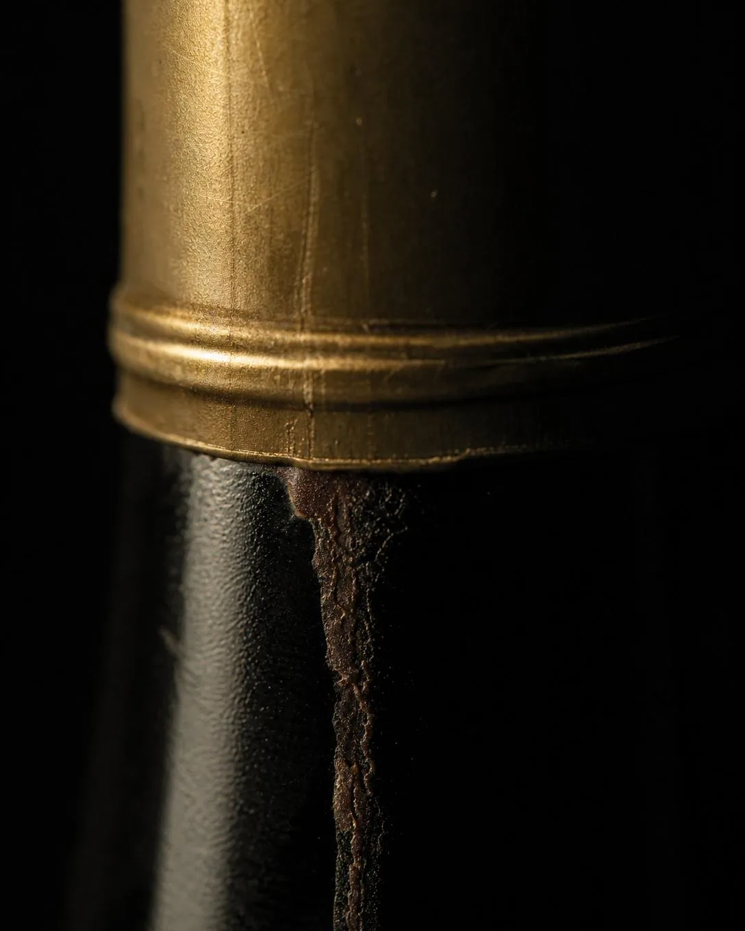 A dried trace of wine below the capsule edge of a dark bottle.