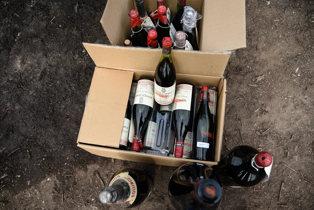 An open cardboard box of seized bottles seen from above, each with an evidence tag, several stamped COUNTERFEIT across the label.